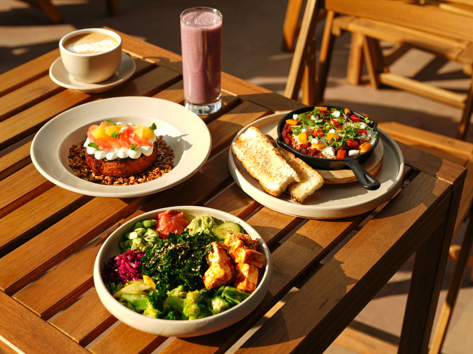 Healthy plant-based brunch table with smoothie, coffee, toast and colorful dishes